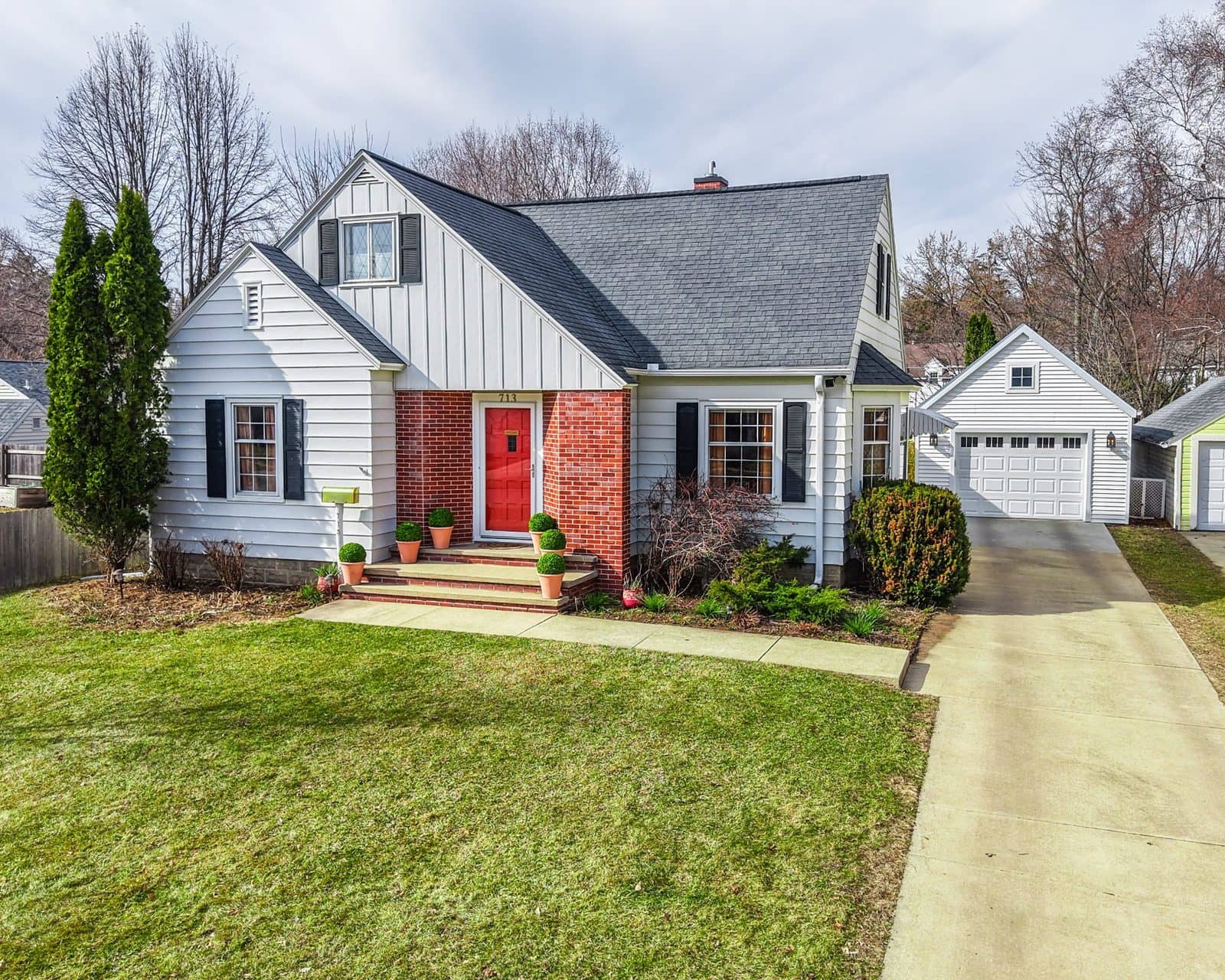 White Cape Cod–style home with a red brick entry and red front door