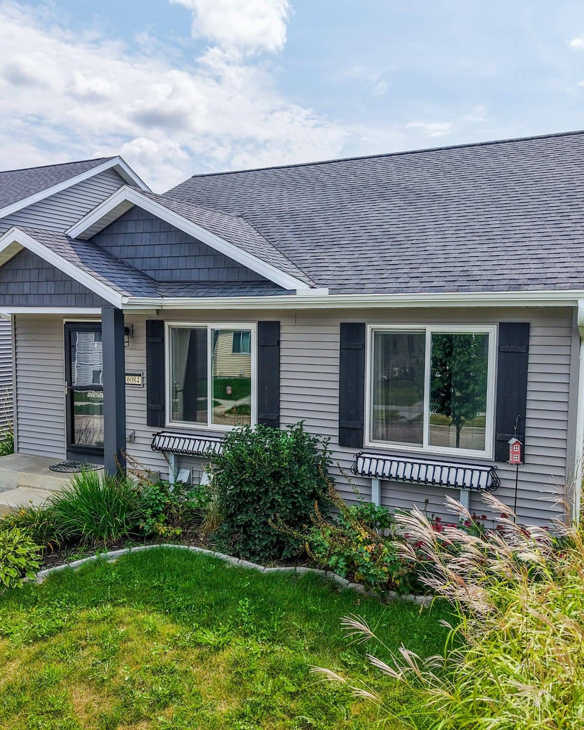 Single-level home with dark shutters and a landscaped front yard
