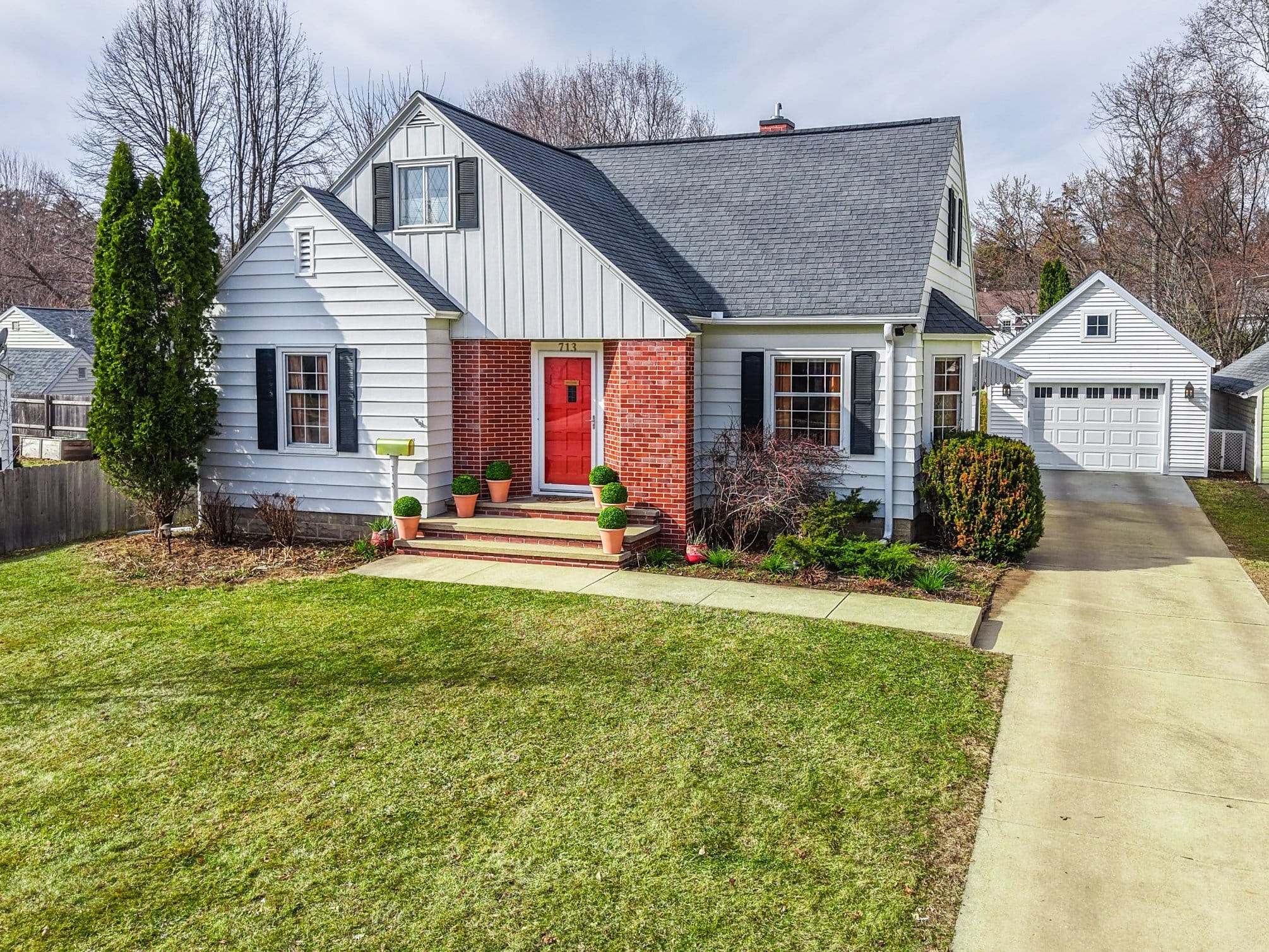 Cape Cod style home with a red front door, brick entry and detached garage