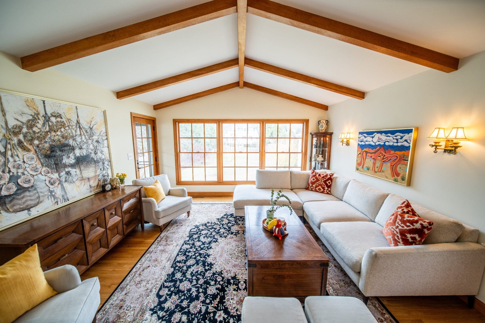 Living room with a vaulted, wood-beamed ceiling and a wall of windows